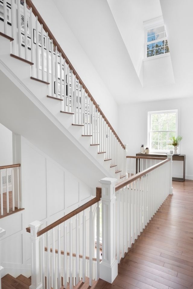 Tall bright white staircase in large modern home by Hibou Design + Co.