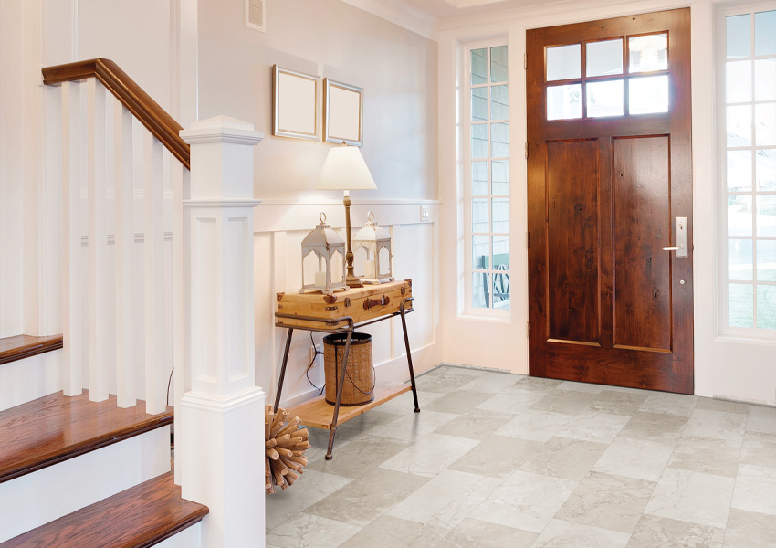 stone look luxury vinyl tile flooring in entryway with small wooden entryway table and lamp